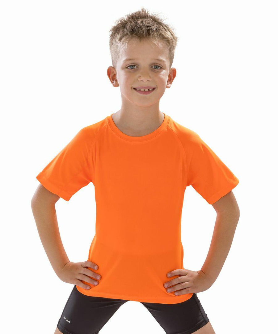 A young boy with short hair stands confidently with hands on hips, wearing a Spiro S287J and black shorts.