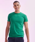 Person wearing a green t-shirt and dark pants, smiling against a light pink background, is holding the SF121 by SF.