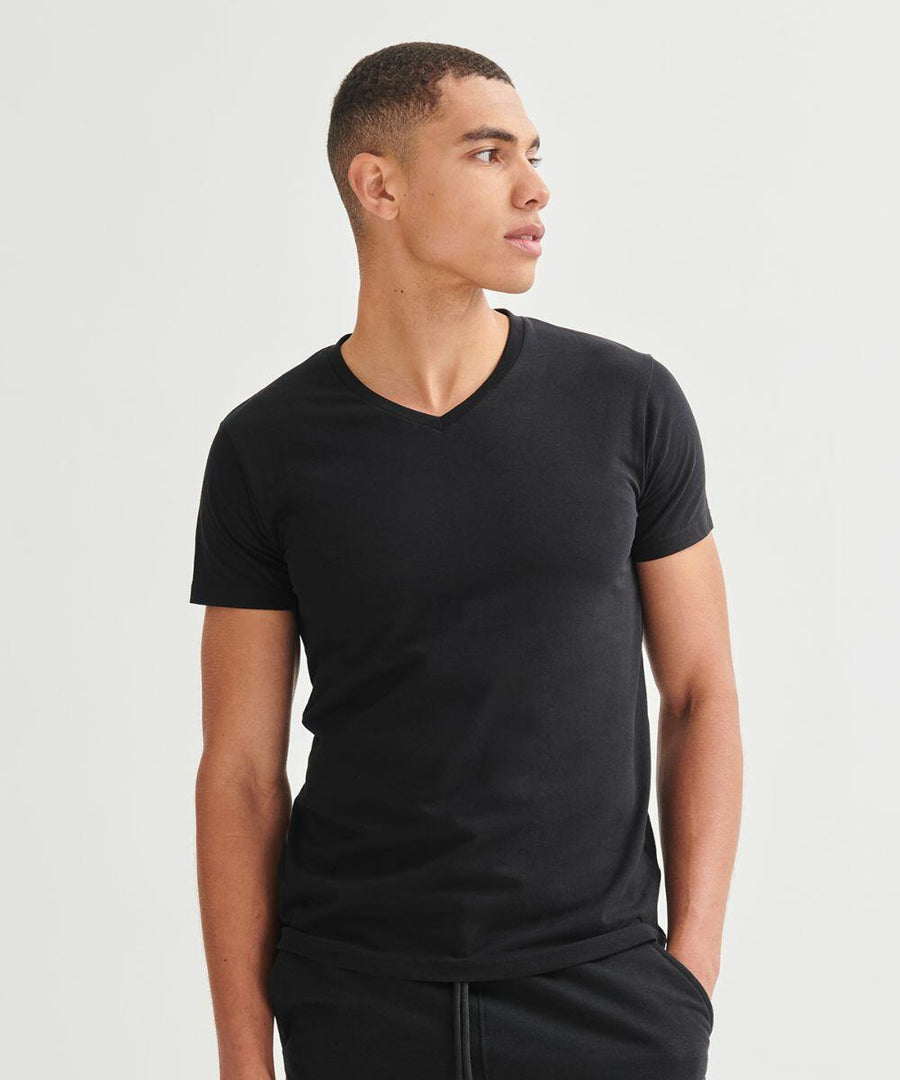 A person wearing a black SF122 T-shirt by SF and looking to their left, standing against a plain white background.