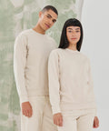 A man and woman stand side by side wearing beige long-sleeve shirts and pants. They are in front of a wall with a green and white abstract design featuring the SF530 by SF.
