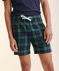 A person is wearing blue and green plaid shorts with a white drawstring, paired with a dark blue SF SFM82 t-shirt.
