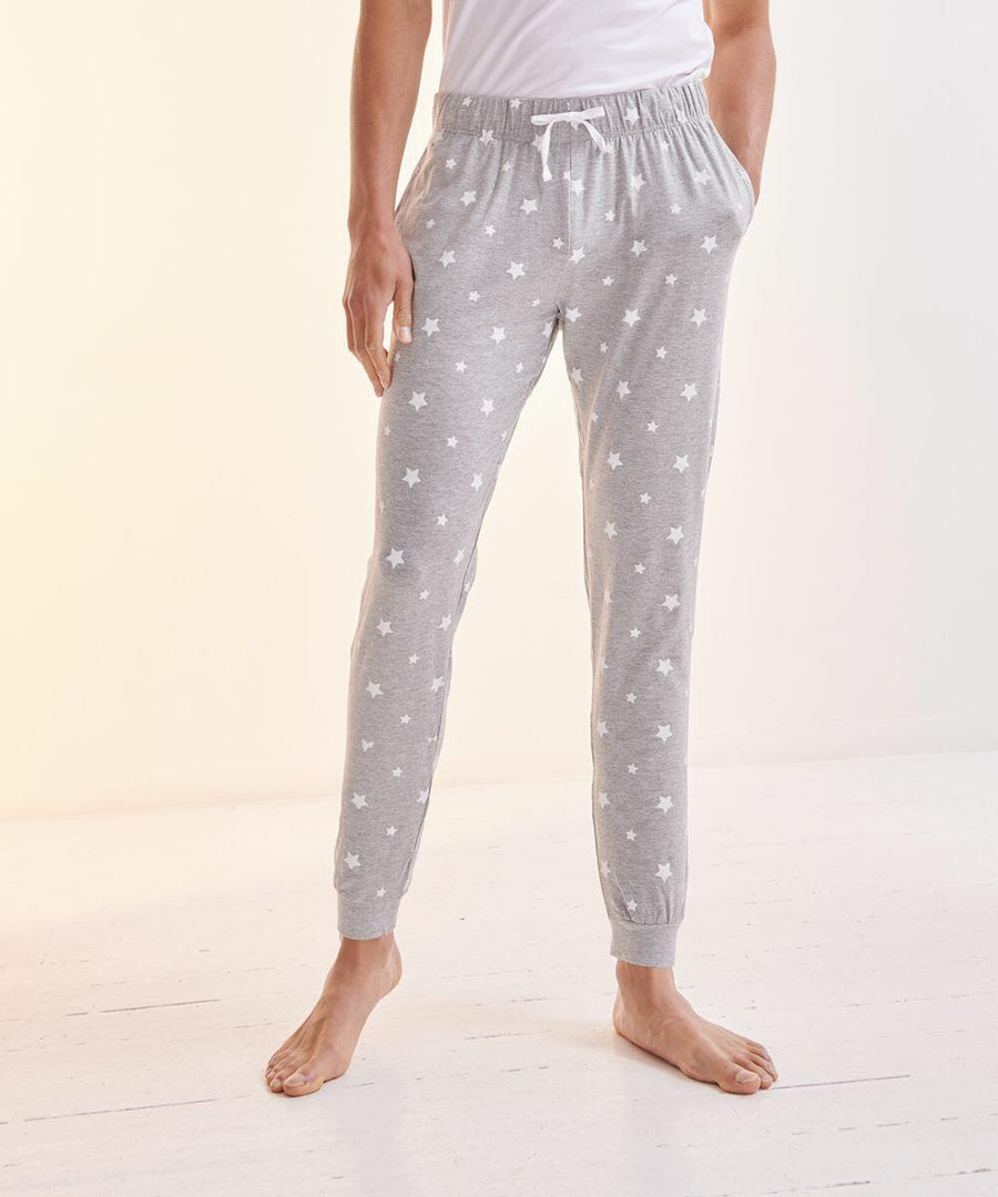 Person standing barefoot on a white floor, wearing light grey, star-patterned SFM86 pajama pants with an elastic waistband and drawstring by SF.