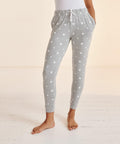 Person wearing SF SK085 grey sweatpants with a white star pattern and white drawstrings, standing barefoot on a white wooden floor.