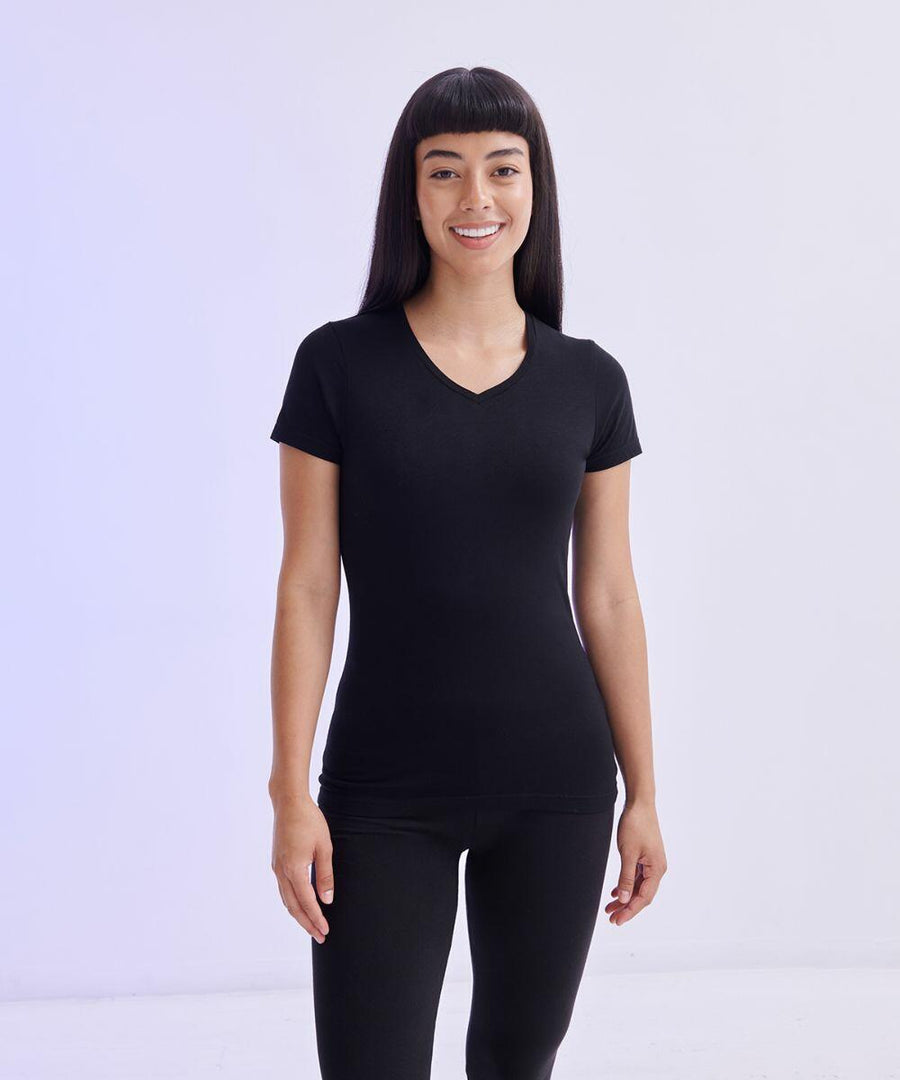 A person with long, straight hair wears a black SK122 by SF and black pants, standing against a plain light-colored background.