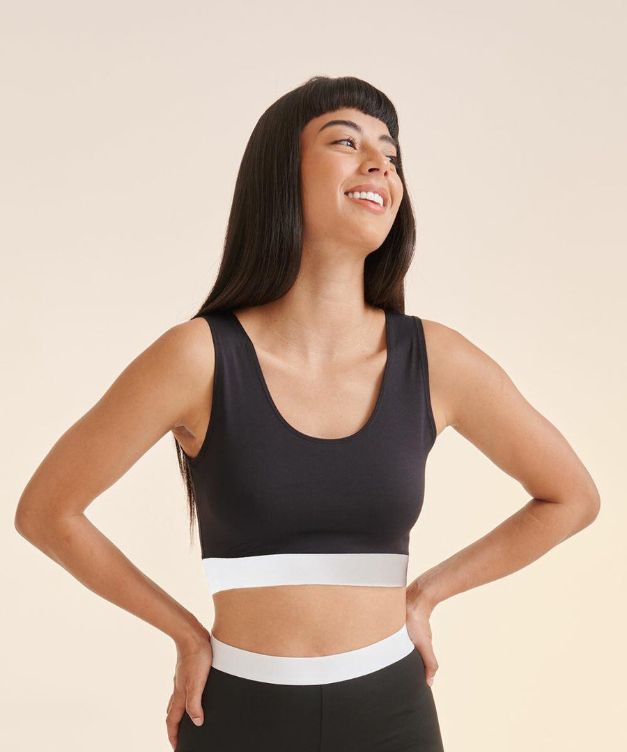 A person with long black hair smiles while looking sideways. They are wearing a black sleeveless top with a white band at the waist from SF, product name SK236.