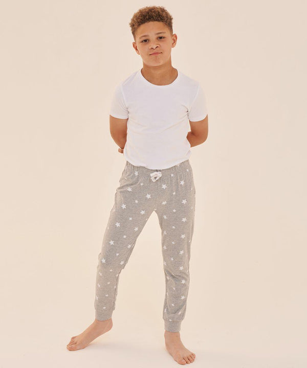 A young boy stands barefoot, wearing a white t-shirt and grey SF Minni SM085 pajama pants with a white star pattern, against a plain light background.