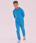 A young boy in a blue SF SM470 stands barefoot against a light pink background.