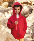 A child wearing a Fruit of the Loom SS225 hooded sweatshirt is holding a stick with three marshmallows, standing in an outdoor rocky area.