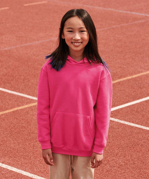 A young person in a bright pink Fruit of the Loom SS273 stands outdoors on a track field.