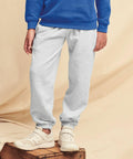 Person wearing a blue Fruit of the Loom SS323 sweatshirt, grey sweatpants, and white sneakers, standing on a wooden crate.
