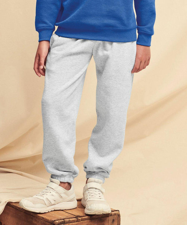 Person wearing a blue Fruit of the Loom SS323 sweatshirt, grey sweatpants, and white sneakers, standing on a wooden crate.