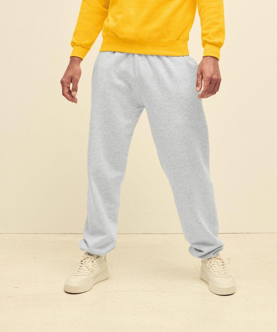 Person in a yellow sweatshirt and light gray SS405 by Fruit of the Loom, standing indoors, showing only the lower half of their body.