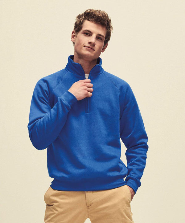Man in a blue Fruit of the Loom SS830 quarter-zip sweater and beige pants, standing against a plain light background.