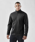 A person wearing a black Stormtech ST075 jacket and dark jeans stands against a plain background.