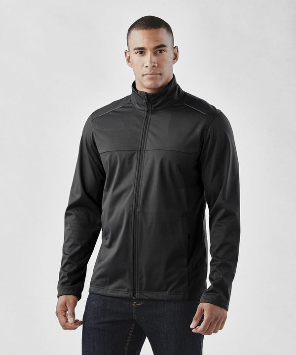 A person wearing a black Stormtech ST075 jacket and dark jeans stands against a plain background.
