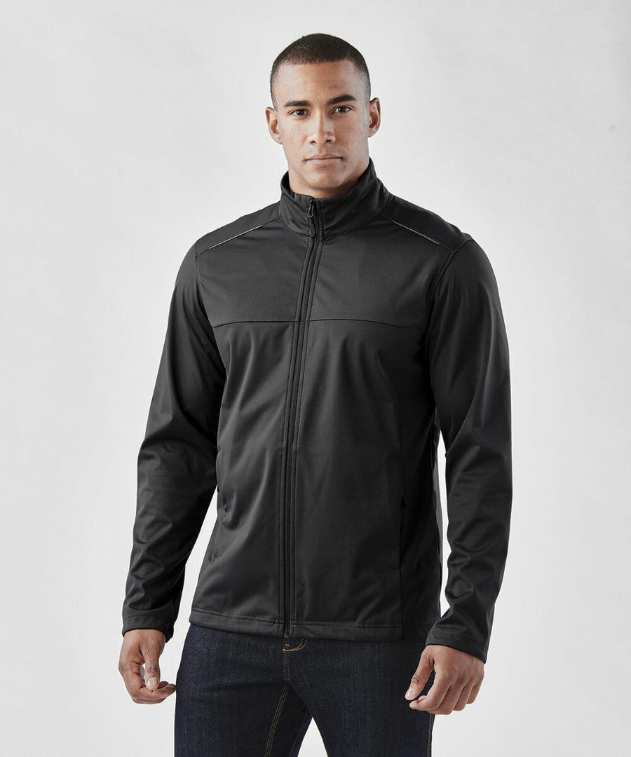 A person wearing a black Stormtech ST075 jacket and dark jeans stands against a plain background.