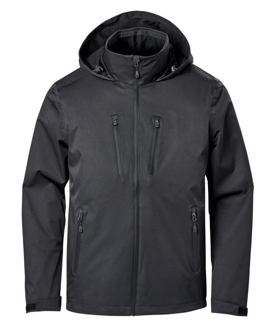 The Softshells jacket is black with a hood, front zip, high collar, and four zipped pockets—two on the chest and two at the waist. It features long sleeves and a minimalist design.