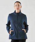 A person stands facing the camera, wearing a navy blue Stormtech ST201 zip-up jacket with hands in the pockets. The background is plain white.