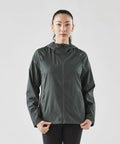 A person wearing a dark green Stormtech ST211 zip-up jacket with a hood stands against a plain background, facing the camera with hands at their sides.