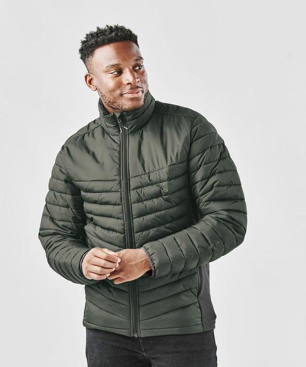 A person wearing a dark green Stormtech ST225 quilted jacket with a full front zipper stands against a plain white background.
