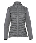 The Softshells jacket is grey with long sleeves, quilted padding on the front and back, a stand-up collar, and smooth fabric on the sleeves and shoulders. It features a zip-up design and is shown against a plain white background.