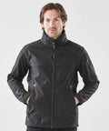 A man with medium-length hair is wearing a black Stormtech ST800 zip-up jacket and standing against a plain white background.