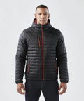 A person wearing a Stormtech ST803 black puffer jacket with red zipper accents stands against a neutral background.