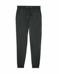 Stanley/Stella SX100 jogger pants in dark green, featuring an elastic waistband, drawstring, and side pockets, laid flat against a white background.