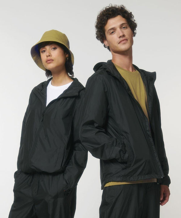 Two individuals in casual attire, wearing black jackets and standing side by side. The person on the left is wearing a yellow SX179 bucket hat by Stanley/Stella. Both have a neutral expression and are facing the camera.