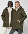Two individuals wearing olive green Stanley/Stella SX204 hooded jackets and light-colored inner layers. The person on the left has a darker complexion with wavy hair, while the person on the right has a lighter complexion with straight hair.