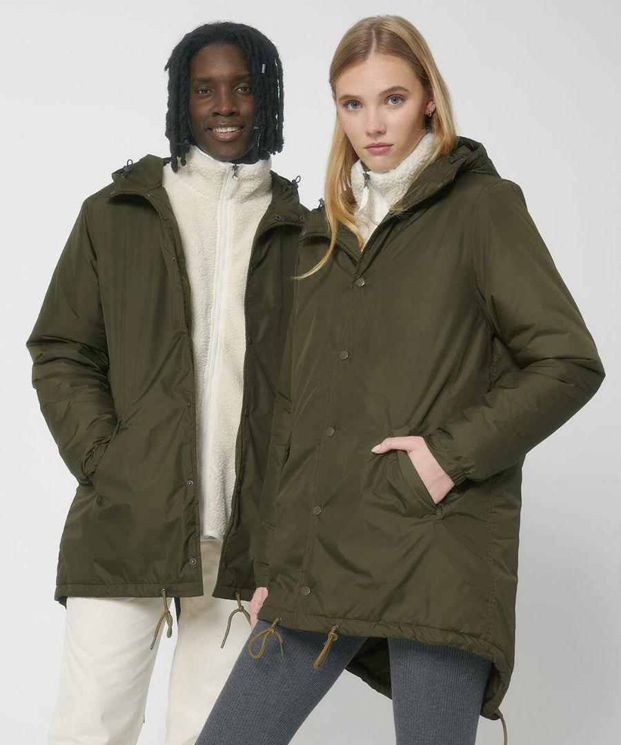 Two individuals wearing olive green Stanley/Stella SX204 hooded jackets and light-colored inner layers. The person on the left has a darker complexion with wavy hair, while the person on the right has a lighter complexion with straight hair.