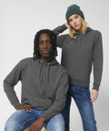 Two people dressed in gray hoodies and blue jeans pose against a plain background. One person is sitting while the other is standing, wearing a green beanie by Stanley/Stella SX219.