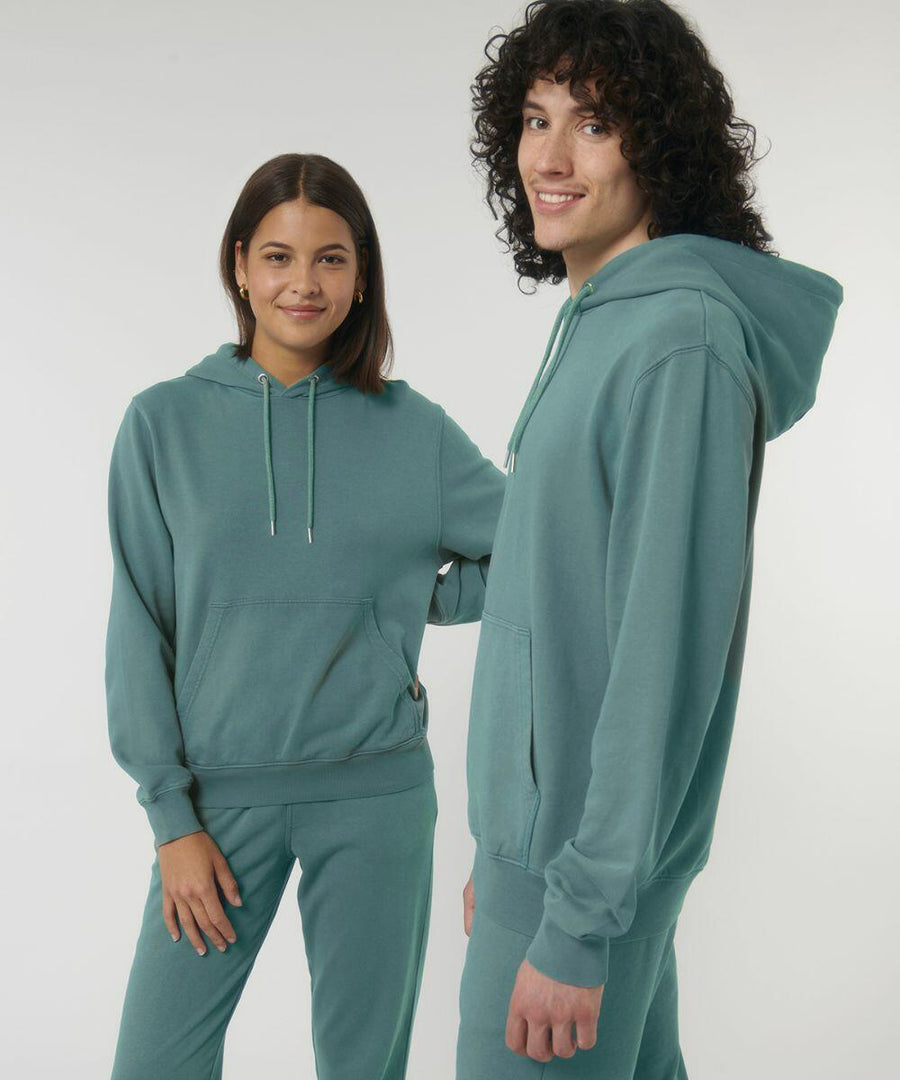 Two individuals wearing matching teal hoodies and sweatpants (SX226 by Stanley/Stella) stand together against a plain background. They both are smiling and looking at the camera.