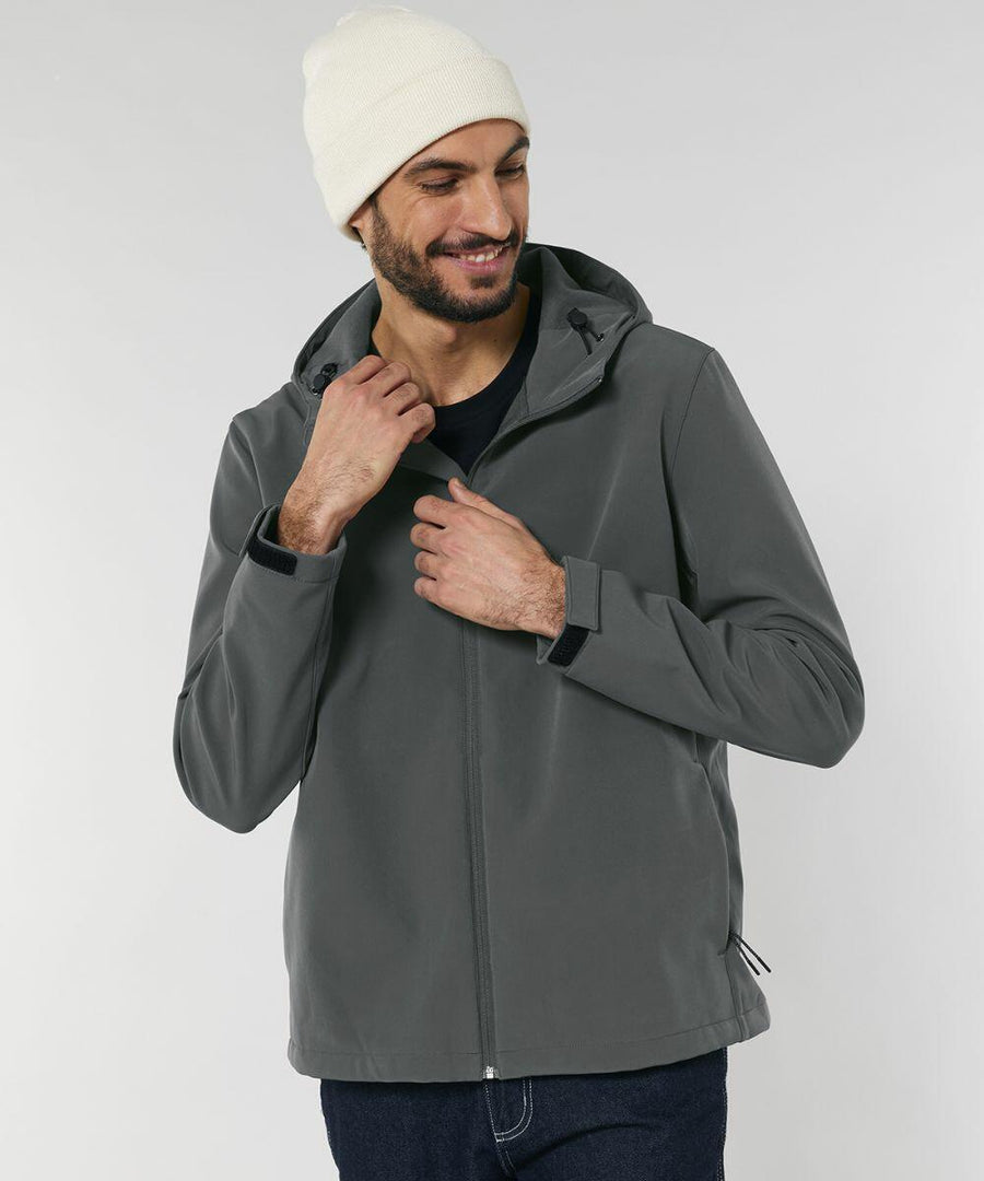 A man wearing a gray jacket and white beanie is standing and smiling while zipping up his SX238 by Stanley/Stella.