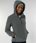 Person wearing a gray Stanley/Stella SX239 zip-up hoodie and a green beanie, smiling with hands in pockets against a plain background.