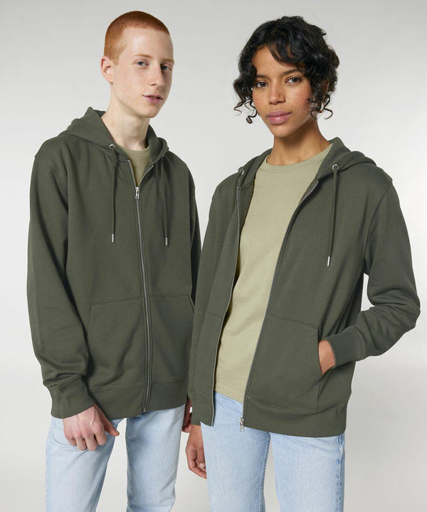 Two people standing side by side, both are wearing Stanley/Stella SX712 green zip-up hoodies, light-colored t-shirts, and light blue jeans, against a plain background.