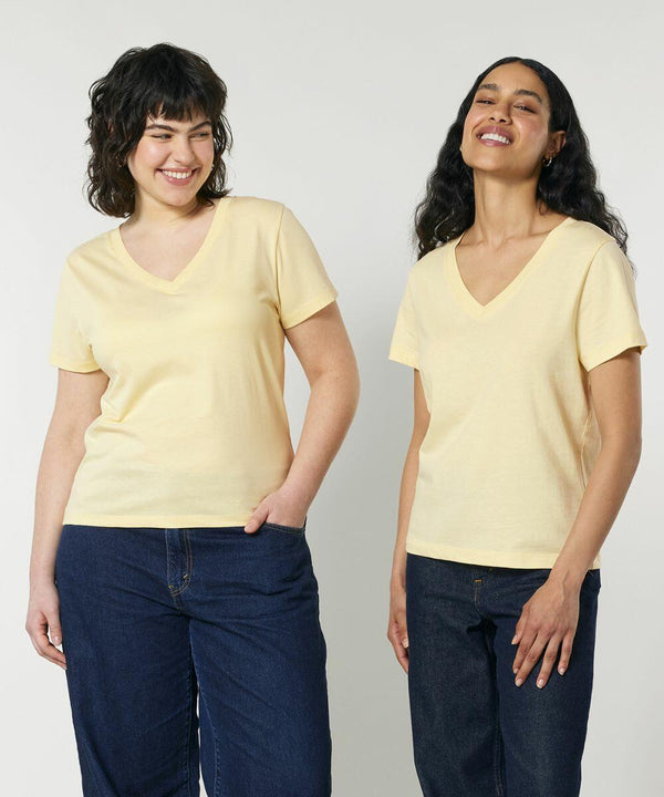 Two people posing and smiling in light yellow Stanley/Stella SX720 V-neck T-shirts. Both are standing against a plain white background, one with hands in pockets and the other with hands by their sides.