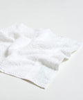 A white, neatly folded Towel City TC001 with a textured surface lies on a plain, light-colored background.