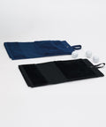 Two Deluxe velour golf towels from Towel City, one in navy blue and one in black, are laid flat with loops at one end. Three white golf balls rest beside the towels on a plain white background.