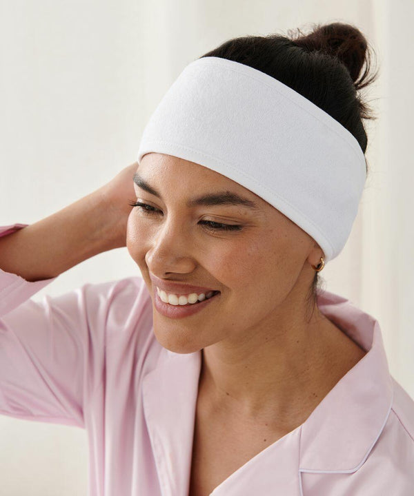 A person wearing a Towel City TC062 and a light pink shirt smiles and touches the back of their head.