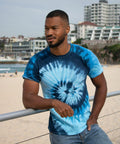 A man in a Colortone TD02M stands by a railing at a beach, with buildings in the background.