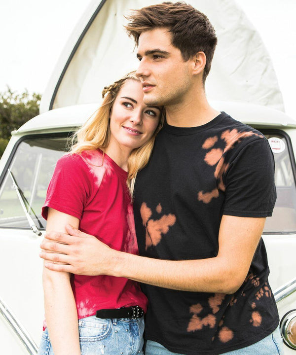 A couple stands in front of a vehicle, with the man wearing a black Colortone TD09M and hugging the woman, who is wearing a red Colortone TD09M.