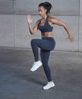 A person in Tombo TL371 athletic wear performs a high-knee exercise in an indoor setting.