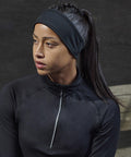 A person wearing a black Tombo TL690 and zip-up athletic top is looking to the side.