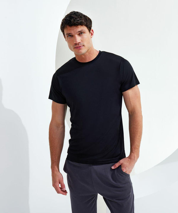 A man standing against a white background, wearing a black Tri-Dri TR010 t-shirt and gray pants, looking at the camera with a neutral expression.