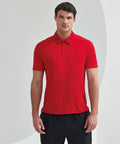 A man in a plain red Tri-Dri TR012 polo shirt and black shorts stands against a neutral background.