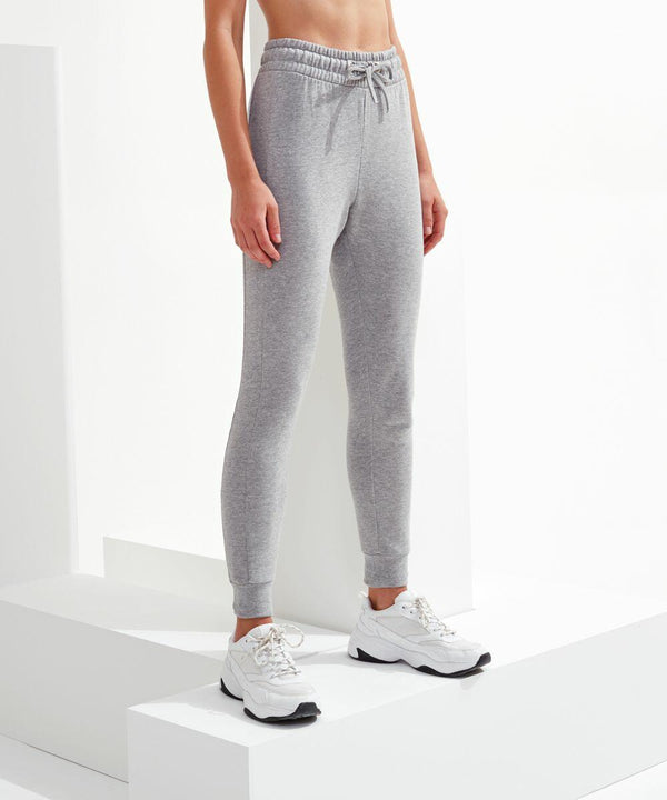 Person wearing gray Tri-Dri TR055 joggers and white sneakers, standing on white steps in a well-lit setting.