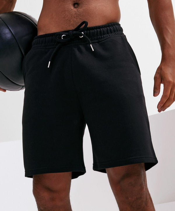 A person wearing black shorts holds a black Tri-Dri TR058 exercise ball, with part of their torso and upper legs visible.