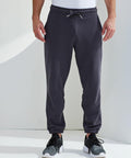 A person wearing Tri-Dri dark gray joggers and Tri-Dri black sneakers stands against a plain background.