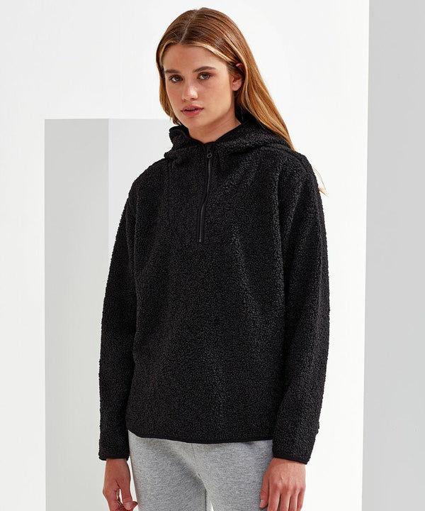 A person stands against a neutral background wearing a black Tri-Dri TR089 pullover hoodie and gray pants.